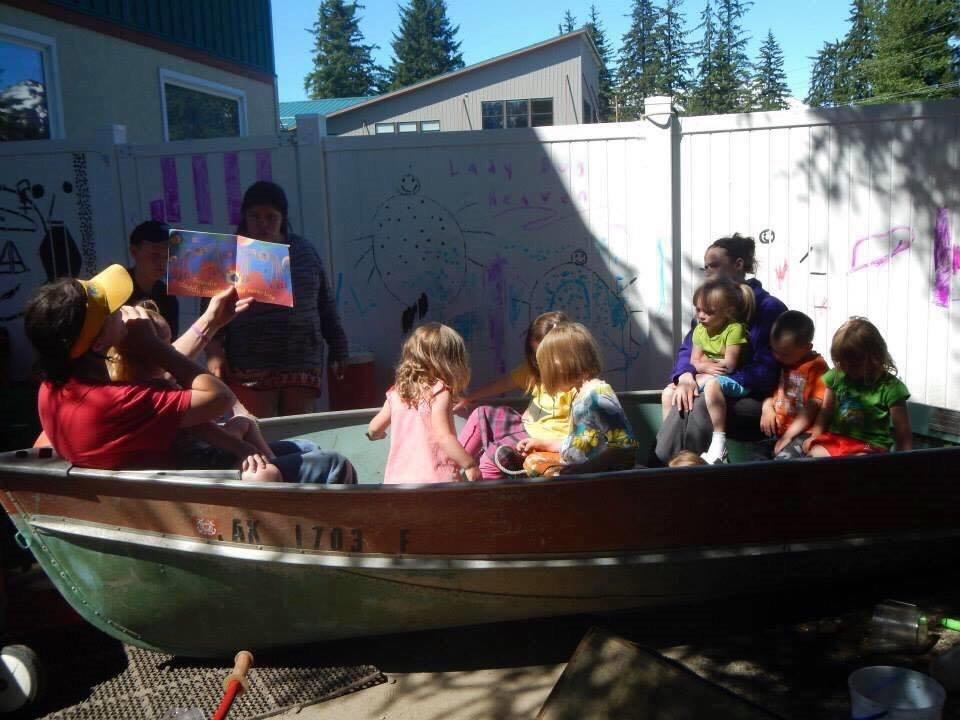 An adult reads to children in a boat