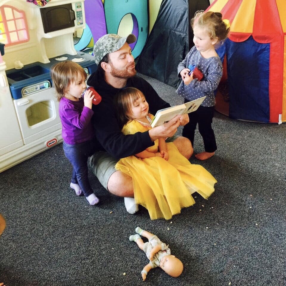 An adult reads with three small children